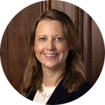 Dr. Lucinda Hiam poses for a headshot in front of a mahogany wall