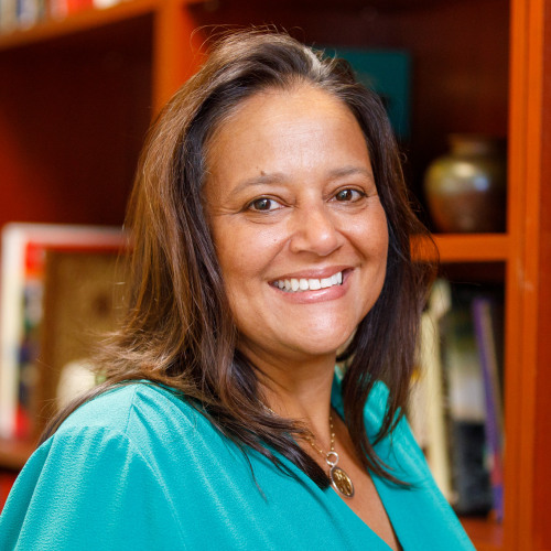 Raquel Robertson stands in front of bookshelves
