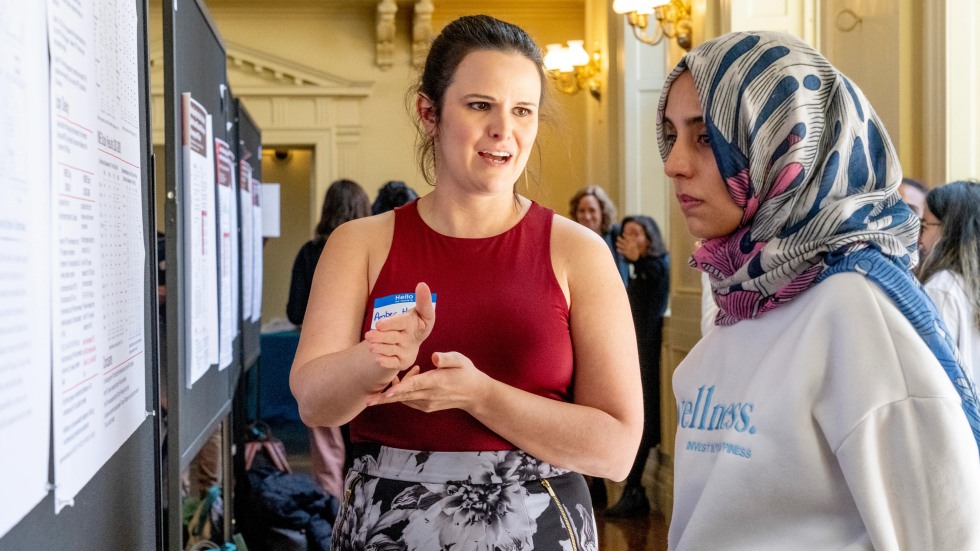 Postdoctoral student explains poster at research event