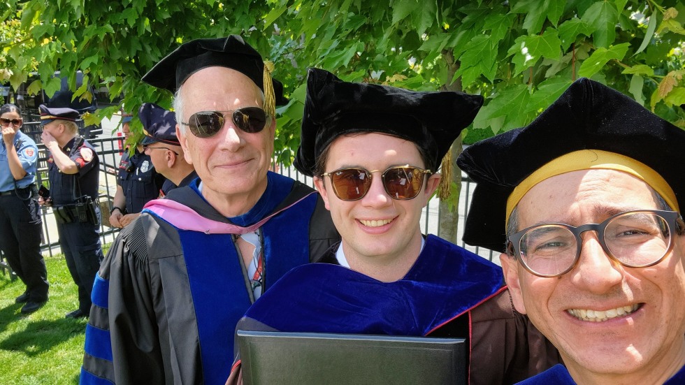 professors and student pose for photo at graduation