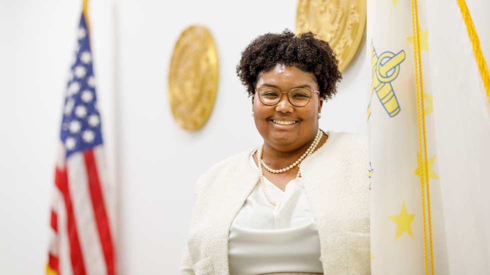 woman stands next to flag in government building