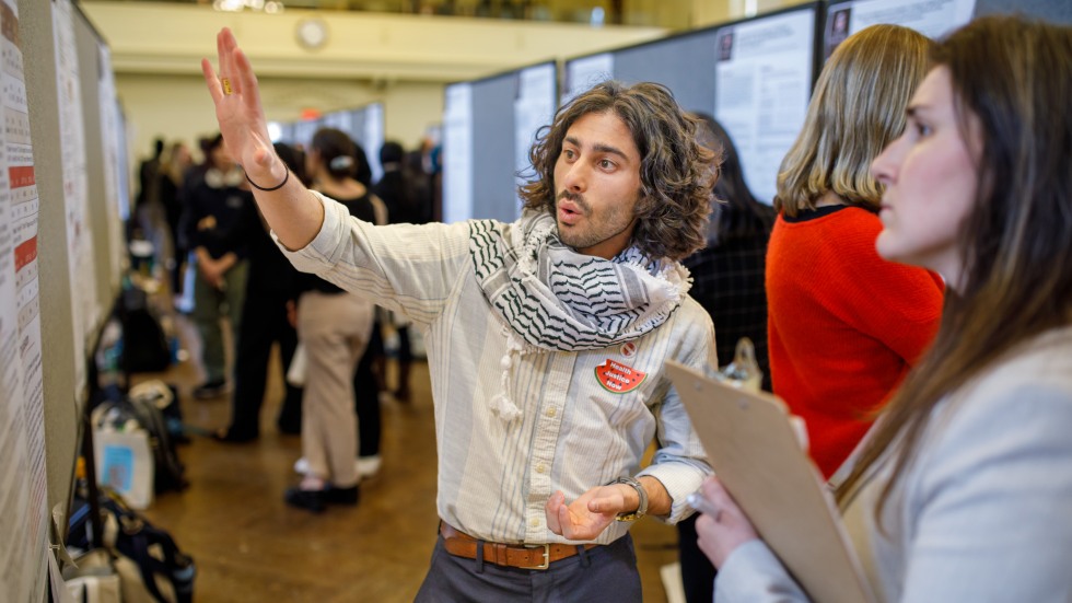 man presents scientific poster to woman