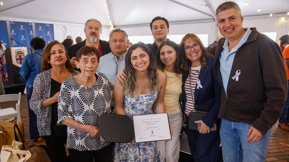 A large family group surrounds a graduating student displaying her award.